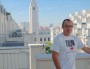 Luc Royet sur la terrasse de son appartement avec la mairie de Villeurbanne en arrière-plan. © Bertrand Enjalbal