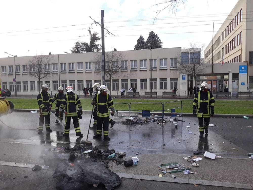 Des pompiers finissent d'éteindre un feu de poubelle devant le lycée Lumière (Lyon 8ème). ©LB/Rue89Lyon