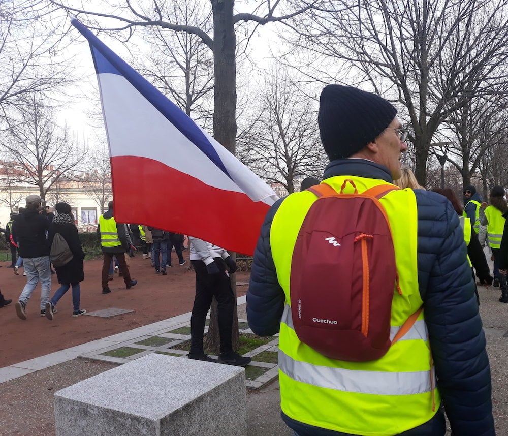 Bruno, place Bellecour, toujours un drapeau français et un gilet jaune. ©LB/Rue89Lyon