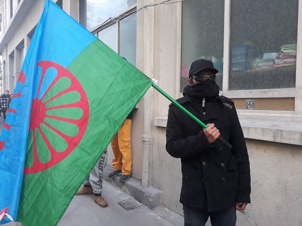 Don-Miglo, le drapeau Rom à la main, avec écharpe et lunettes de piscine pour se protéger des gaz lacrymogènes. ©LB/Rue89Lyon