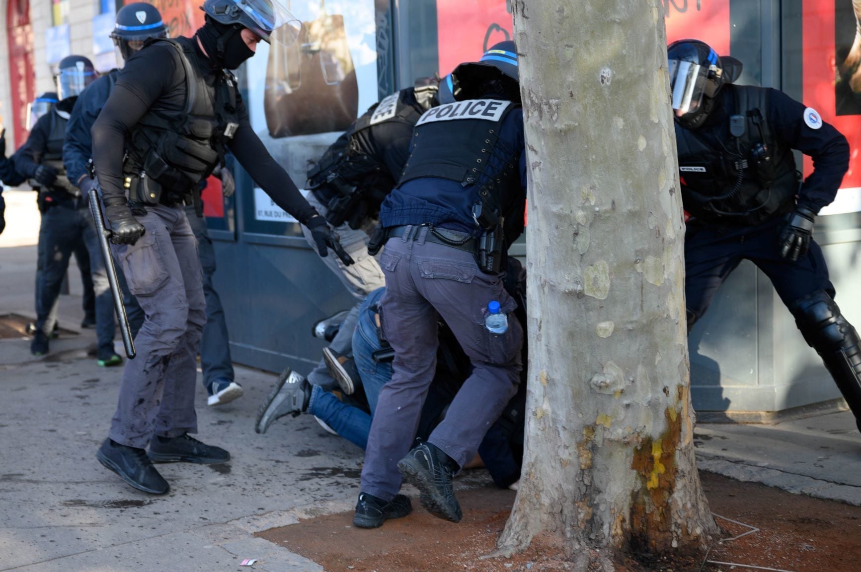 Arthur battu par des CRS entre le kiosque à journaux et un arbre de la place Bellecour. Crédit : Bastien Doudaine.