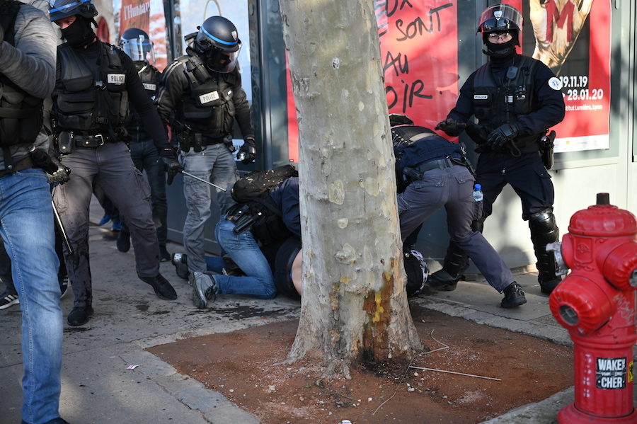 le policier qui semble être l'auteur probable du coup de matraque ; la jambe gauche de son pantalon est maculée de sang