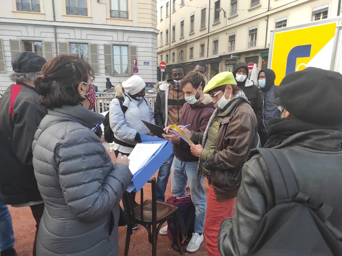 Place Bellecour, des occupants du squat Maurice Scève ont rendez-vous avec un employé de la Métropole (celui avec l'ordinateur) pour être dirigé vers un hôtel ©GB/Rue89Lyon