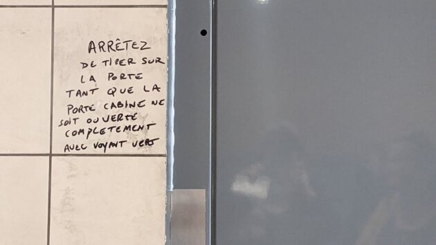 Un message non signé écrit à-même le mur au sujet de l'ascenseur toujours en panne dans un logement de LMH à Lyon 8è. ©LS/Rue89Lyon