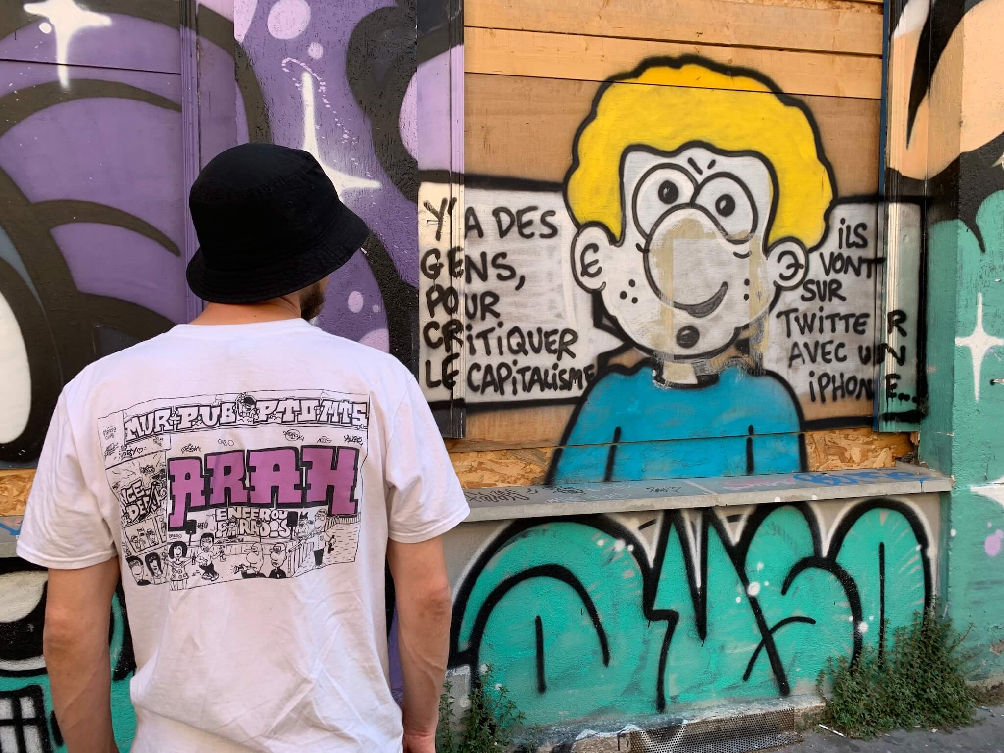 Le graffeur Tapas Nocturne, aux côtés de l'une de ses BD ironique taguée dans le 7e arrondissement de Lyon. ©MA/Rue89Lyon