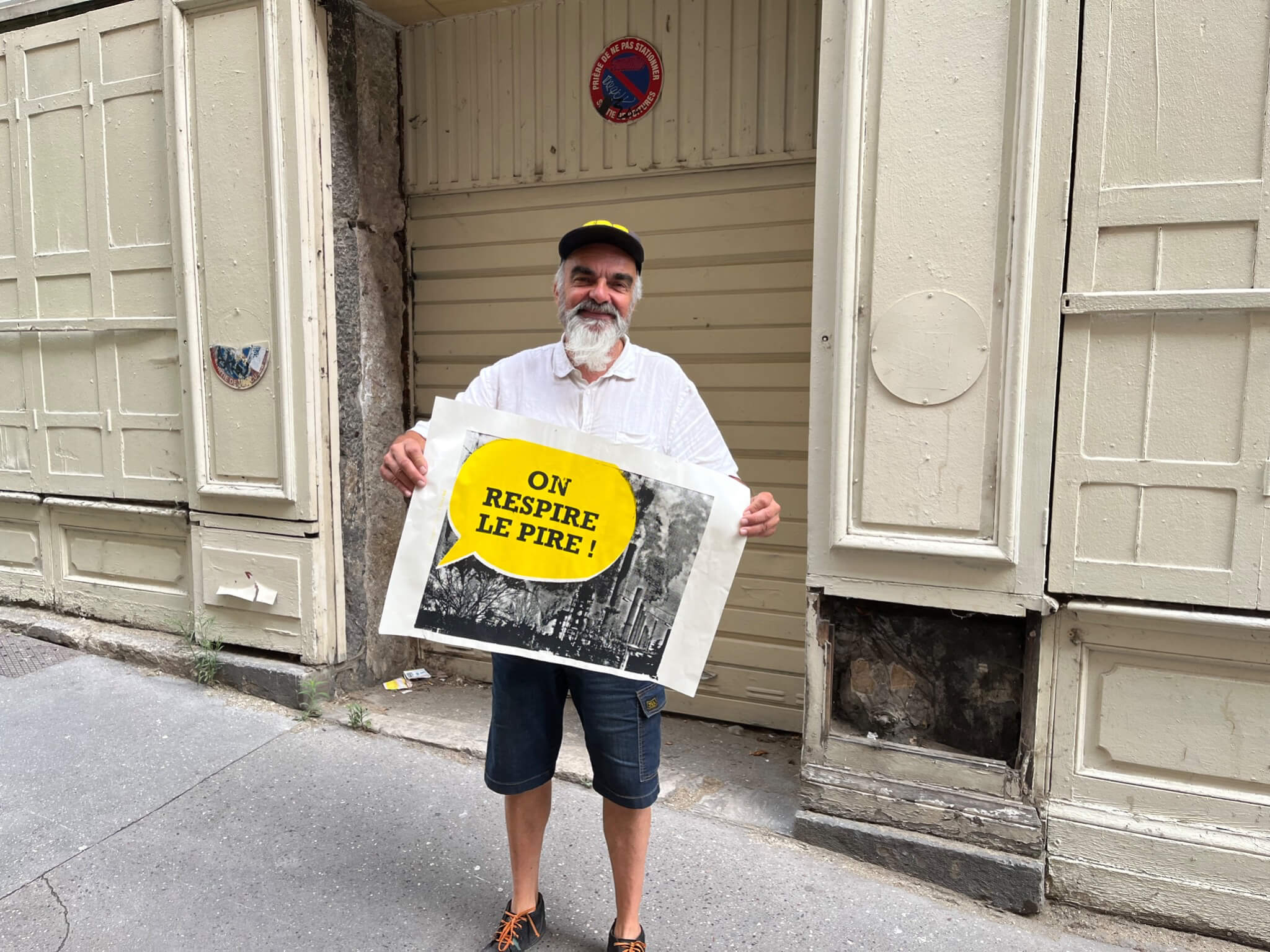 Papyart tient l'une de ses affiches sérigraphiée faisant référence à la pollution de l'air à Feyzin. ©LB/Rue89Lyon