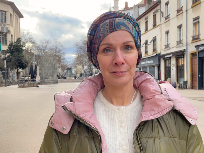 Karima, porte-parole du pacte Lyon respirable. Elle porte un turban, une doudoune verte et rose, et pose devant une rue ©MA/Rue89Lyon