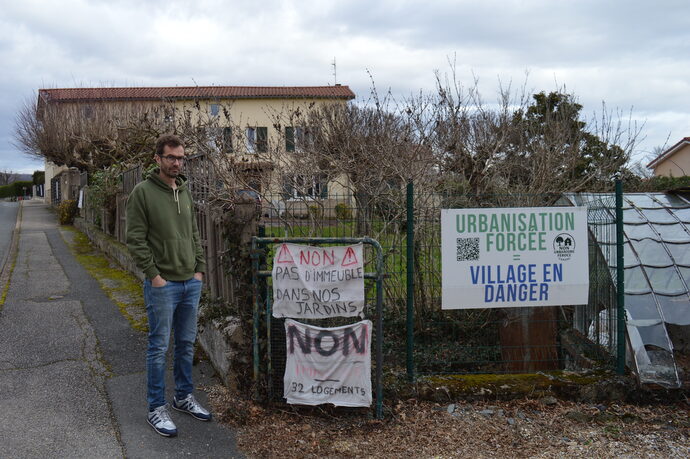 Laurent Morel, devant les affiches installées devant sa maison pour protester contre la construction d'un immeuble à côté de chez lui. ©MA/Rue89Lyon